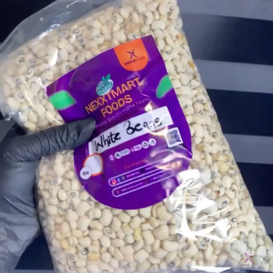 Bag of white beans with a purple 'NextSmart Foods' label held by a gloved hand against a striped background.